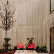 Residential courtyard in a concrete home with planting and red chairs
