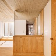 Interior with wood flooring and built-in furniture, white walls and exposed board-formed concrete ceiling