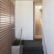 Top of a staircase with dark floors, white walls and timber-slatted siding