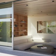 Outdoor terrace with sliding glass doors leading to a living room with a corner sofa