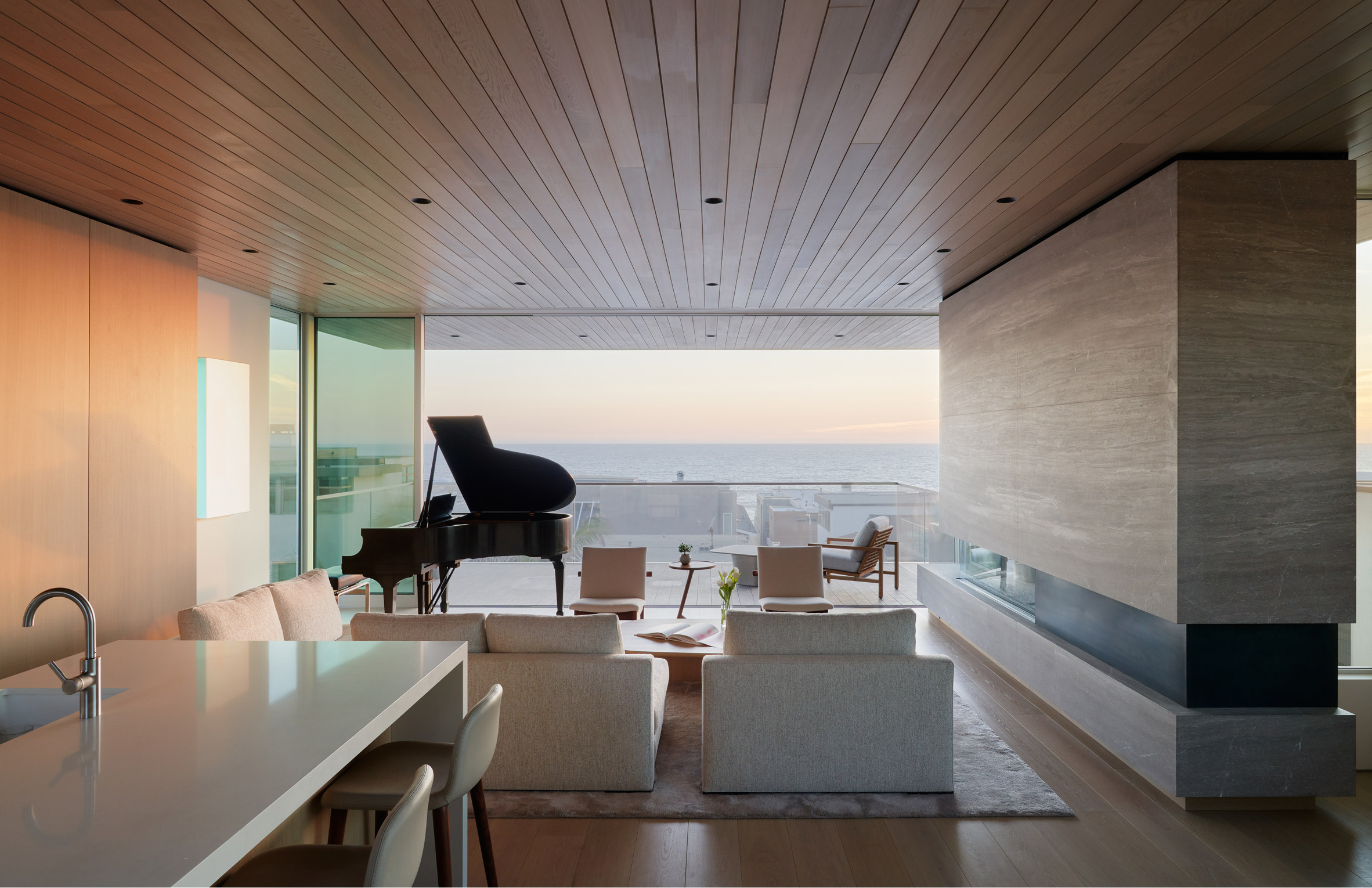 Living room in a Californian home with seating, a piano, and glass sliding doors with views of the city skyline