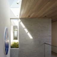 Top of a staircase with wood-line ceilings, stone walls and a skylight