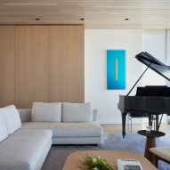 Living room with built-in wood storage, a grey sofa and a piano