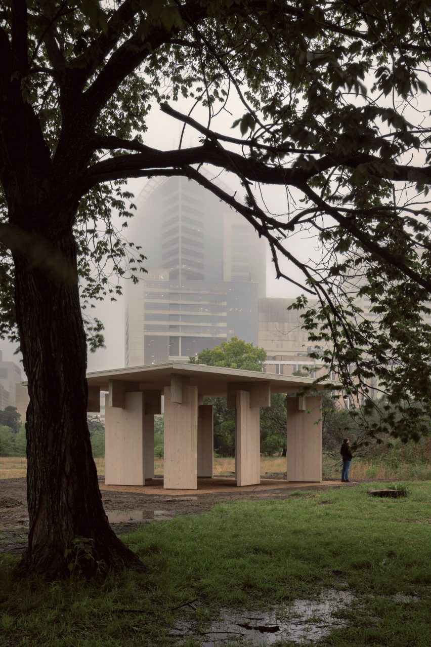A timber pavilion in front of a tall building