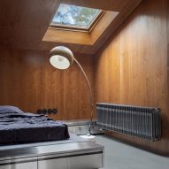 Bed in wood-panelled bedroom with retro lighting