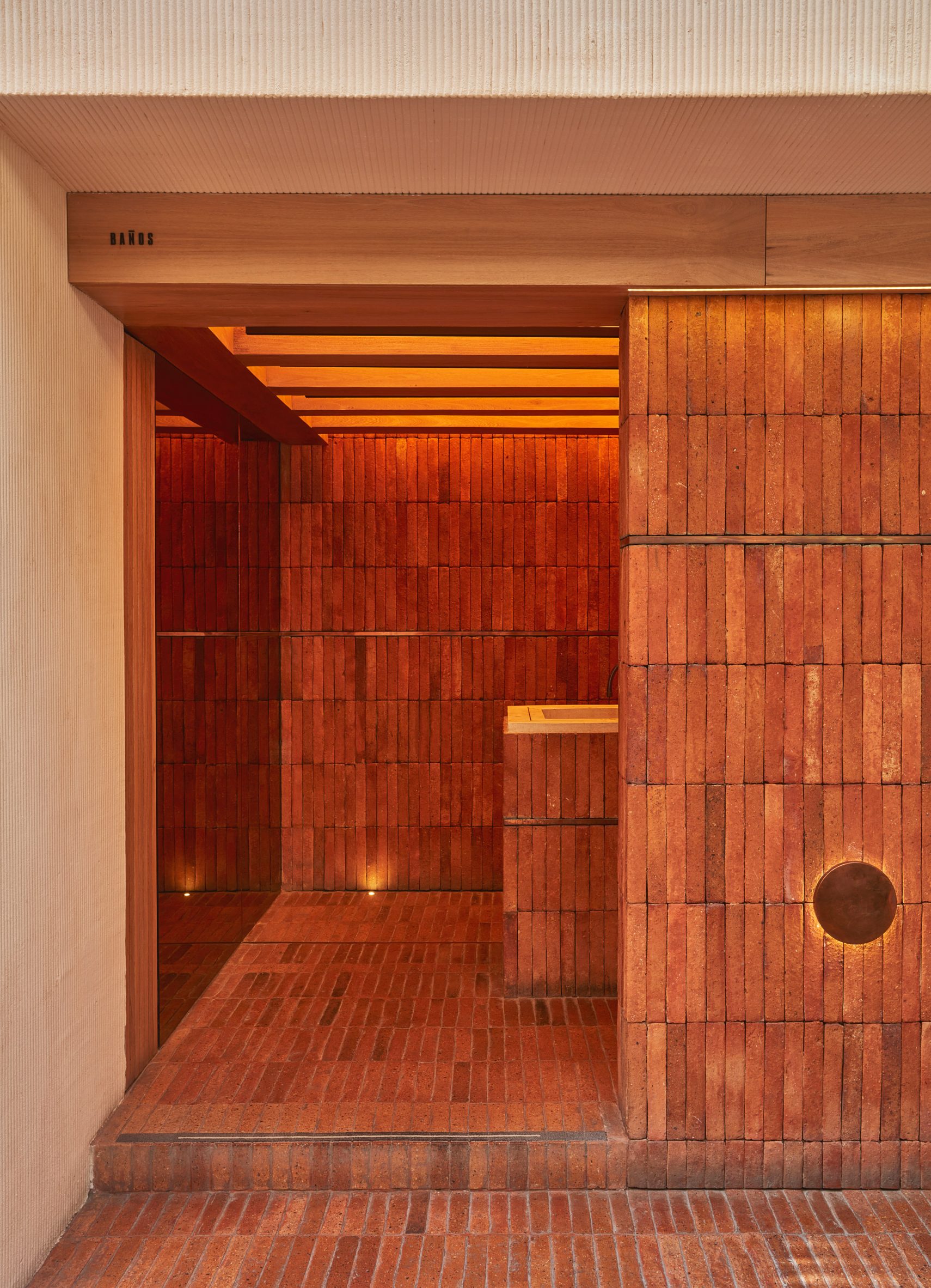 The entrance to a bathrooom that is clad is warm brick