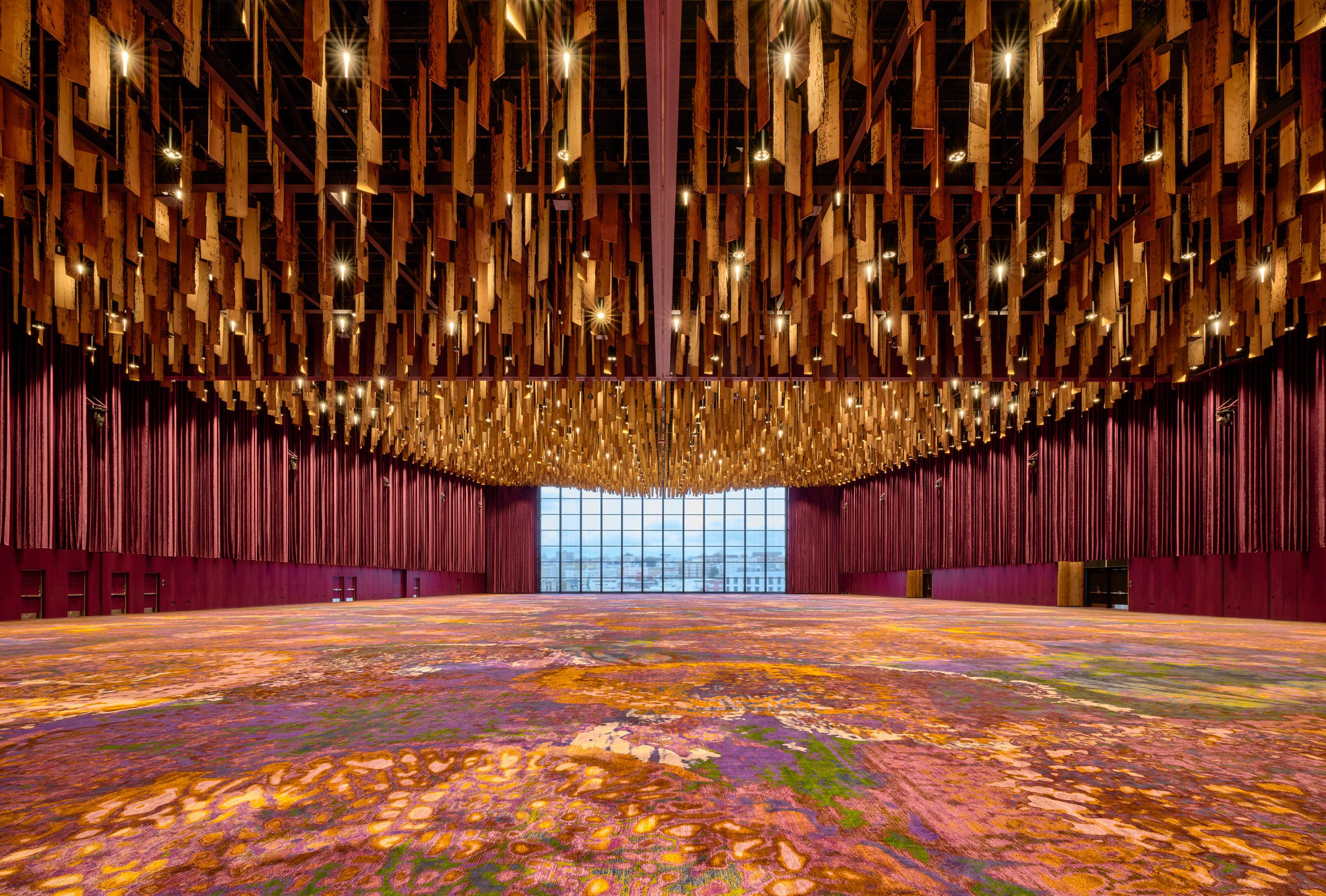 Large room with wooden planks hanging from ceiling with a bright carpet