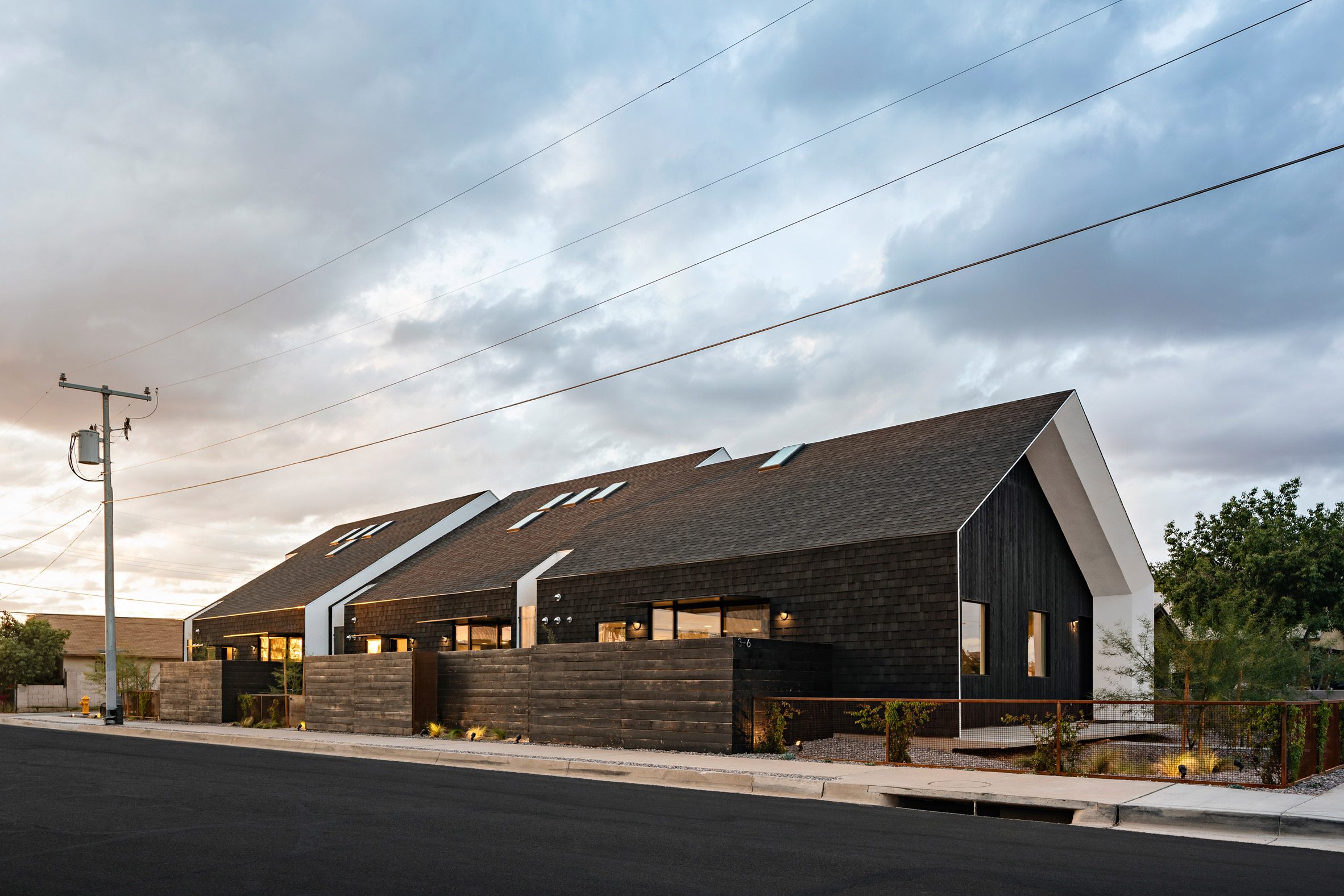 Pitched roof house clad in black wood and asphalt shingles