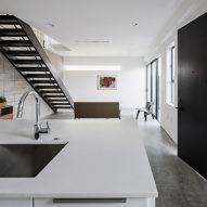 Open-plan kitchen and dining room with a white island and steel staircase