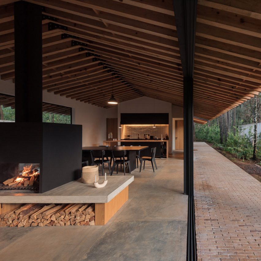Open-plan living interior with stone floors, timber pitched roof and glazed walls leading outside