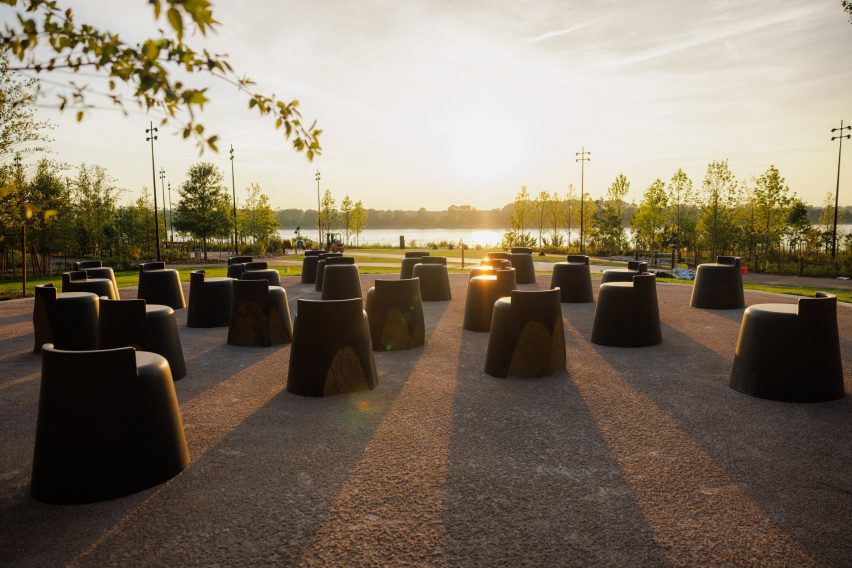 Black chairs on sidewalk by Theaster Gates at sunset