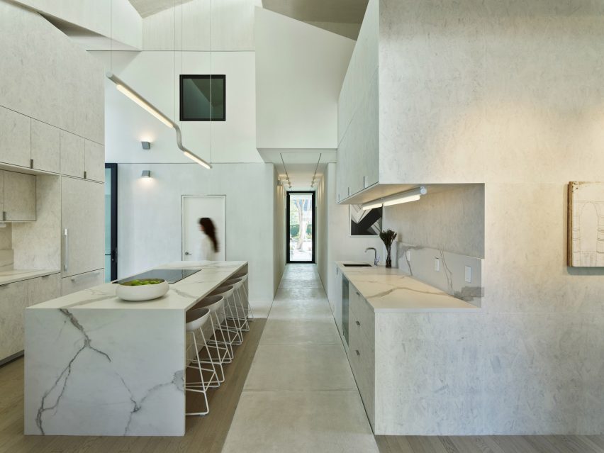 Marble kitchen divided by a concrete footpath by The LADG