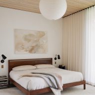Bedroom with white walls, timber ceiling and dark timber bed frame