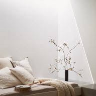 Concrete bench seating in a white room with white cushions and blanket