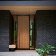 Wooden front door to a house with black brick walls