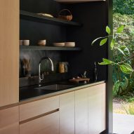 Kitchen with wooden units and black shelving and worktops