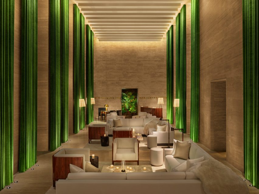Travertine-lined lobby with tall ceiling and full-height green curtains