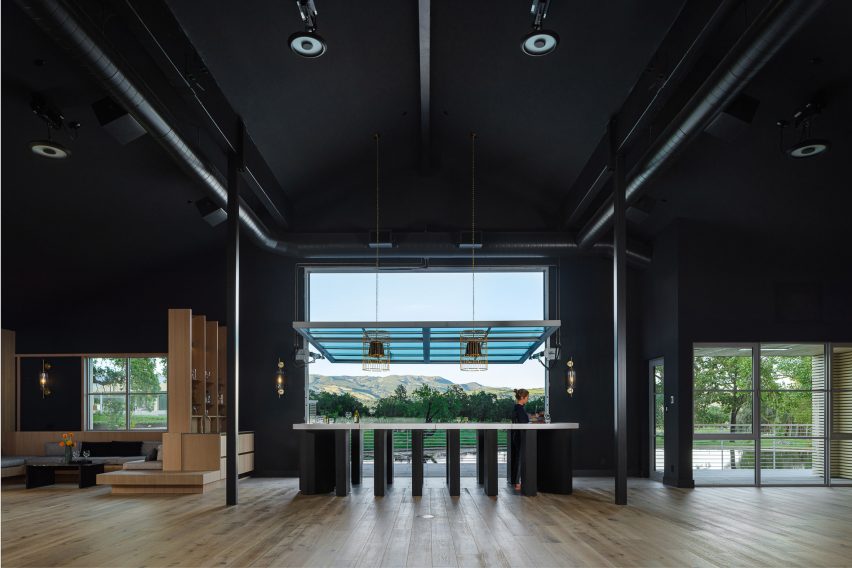 Black open-plan space in a timber barn with large window openings