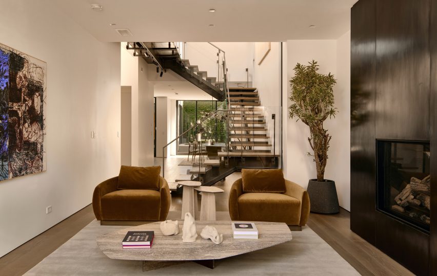 Living room with bronze fireplace, two armchairs and transparent staircase