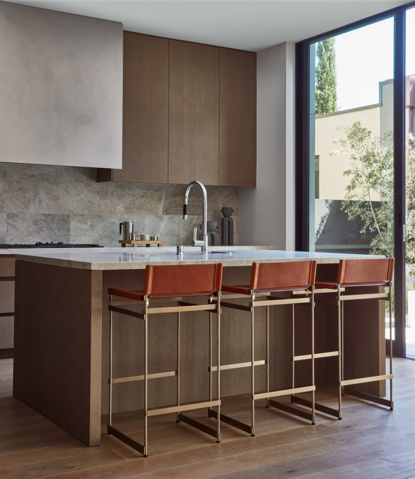 Kitchen with wooden cabinets and thin metal stools on the island