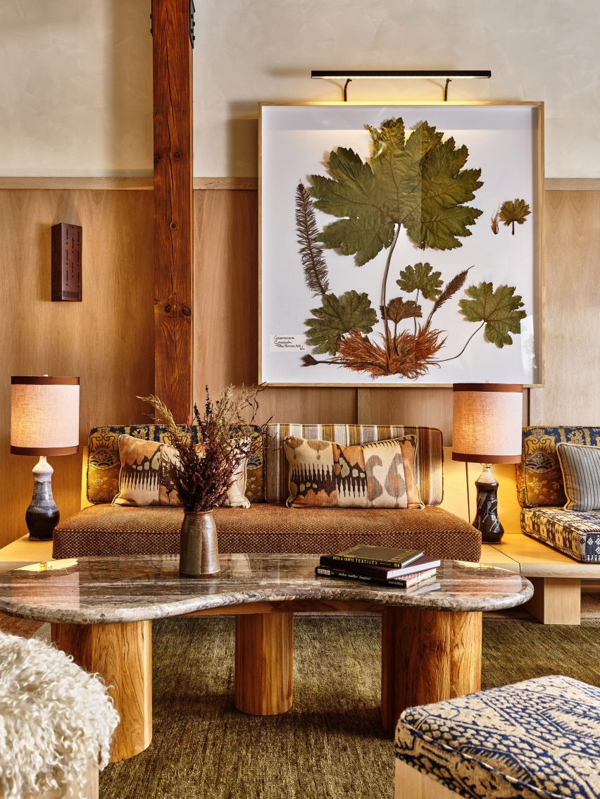 Framed pressed botanicals hang on a wall above earth-toned furniture