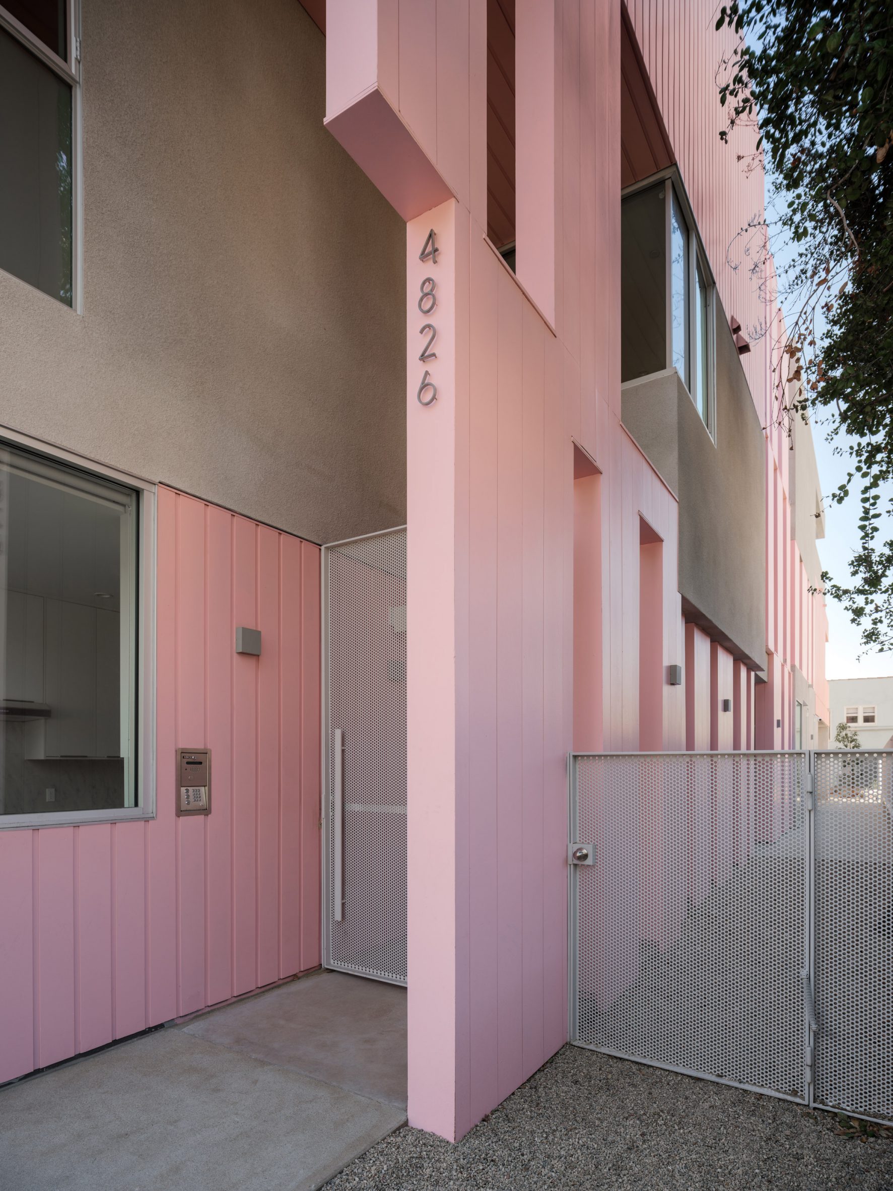 Front entrance to a pink and grey apartment building by Yu2e