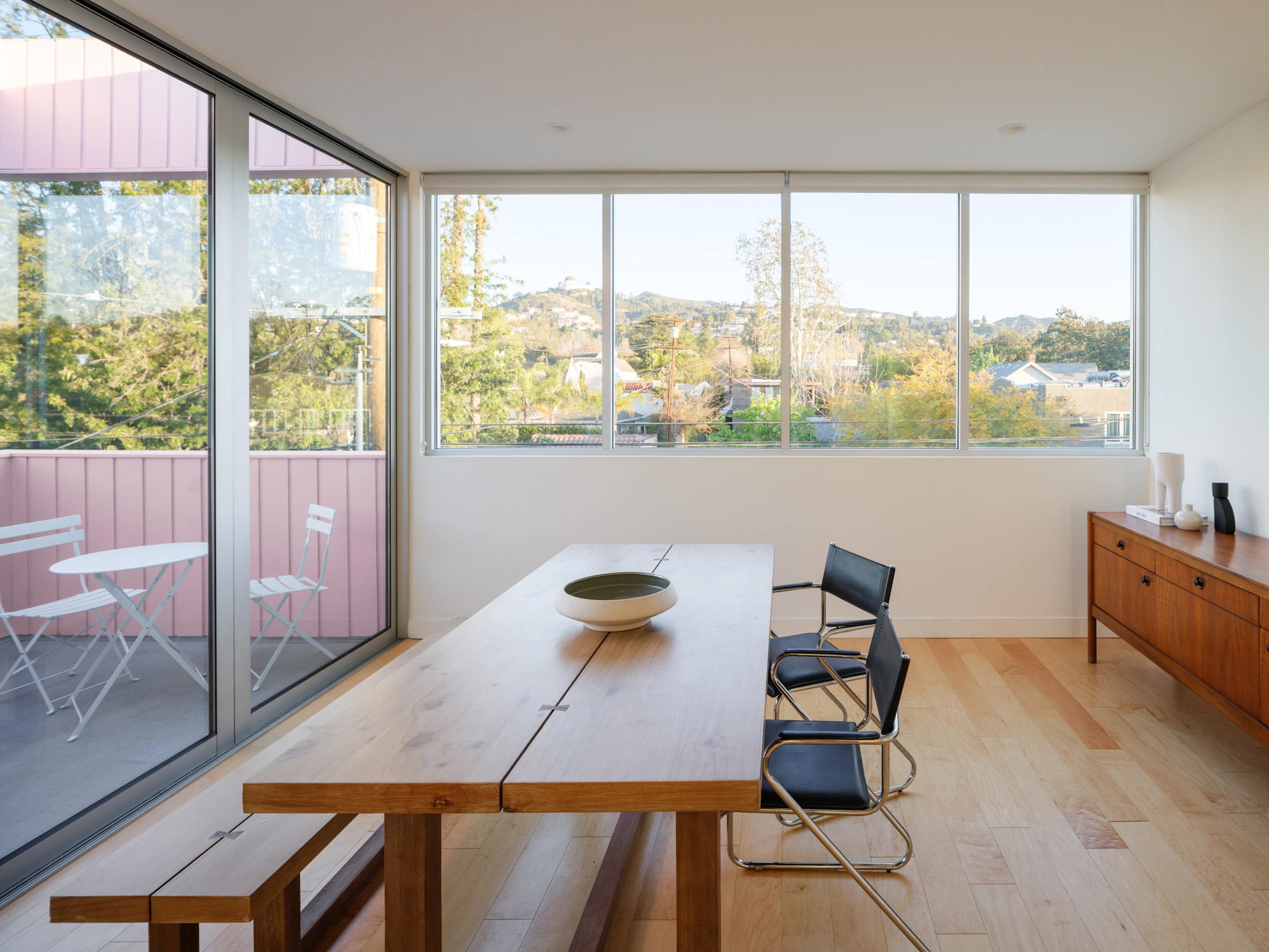 Dining room with wooden floors and sliding glass doors leading to a terrace with pink walls