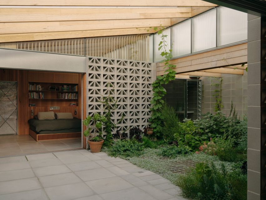 Garden courtyard surrounded by breeze block walls leading to a bedroom at the Sunday home by Architecture Architecture