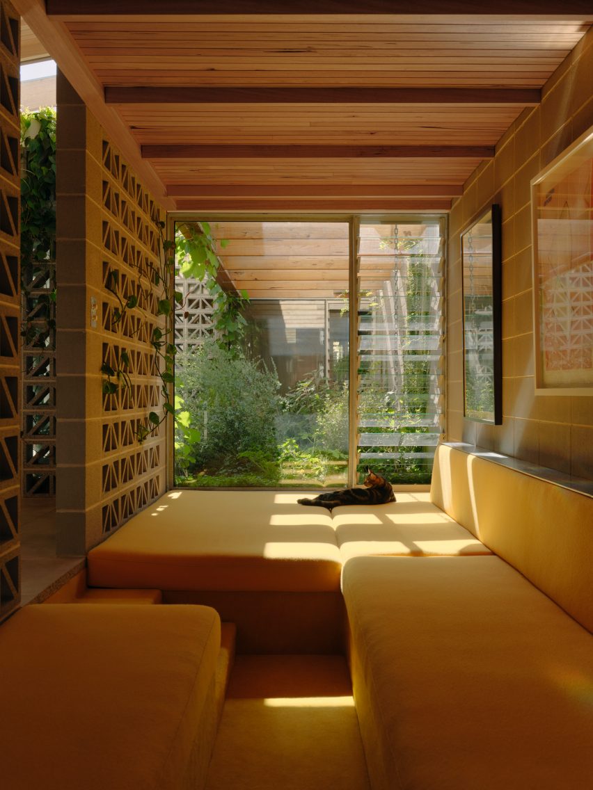 Yellow cushioned window seating nook with perforated breeze block walls by Architecture Architecture
