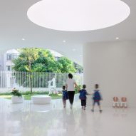 White semi-open outdoor space at the Kindergarten of Museum Forest by Atelier Apeiron
