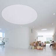 White internal space with a circular light at the Kindergarten of Museum Forest by Atelier Apeiron