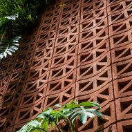 Red perforated cement block facade covered in plants