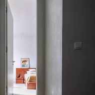 Grey plastered corridor with an open door leading to a bedroom