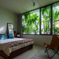 Bedroom with large windows covered by verdant planting