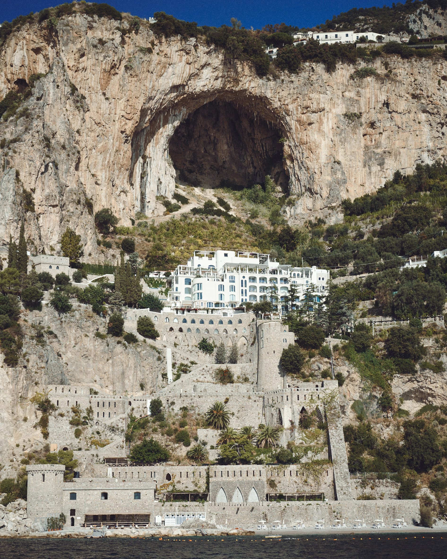 White hotel sat below a large cave and above medieval fortifications