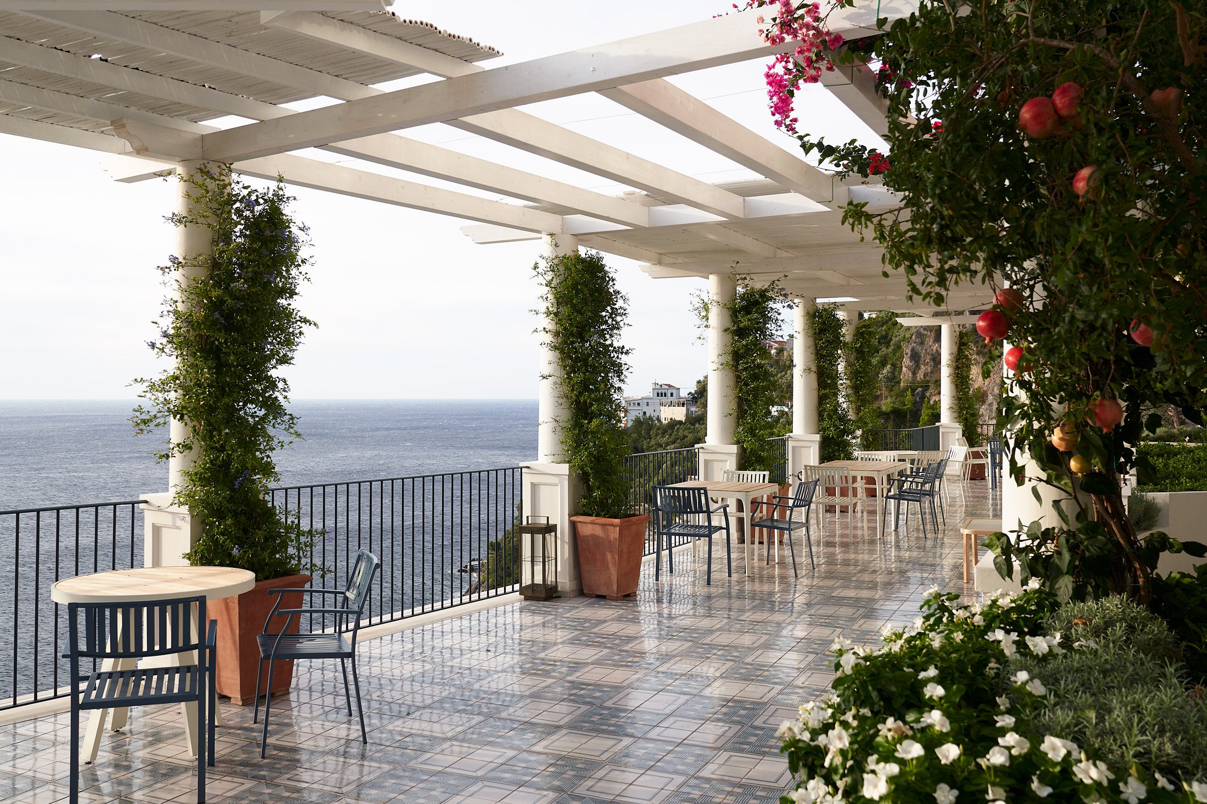Large terrace with tiled floor covered by a white pergola