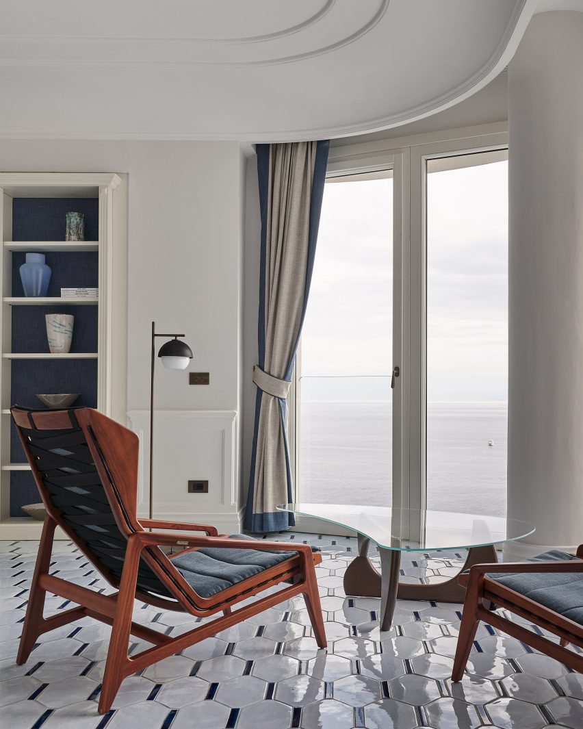 Mid-century armchairs facing a window with a sea view