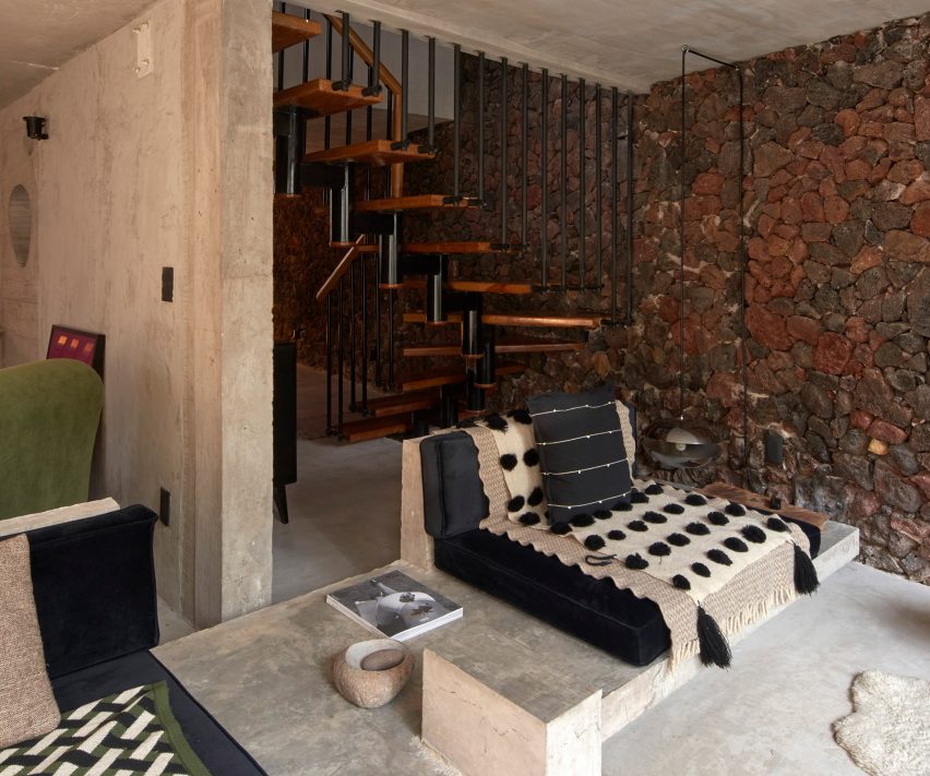 A living room with a wall of exposed stone and a concrete couch