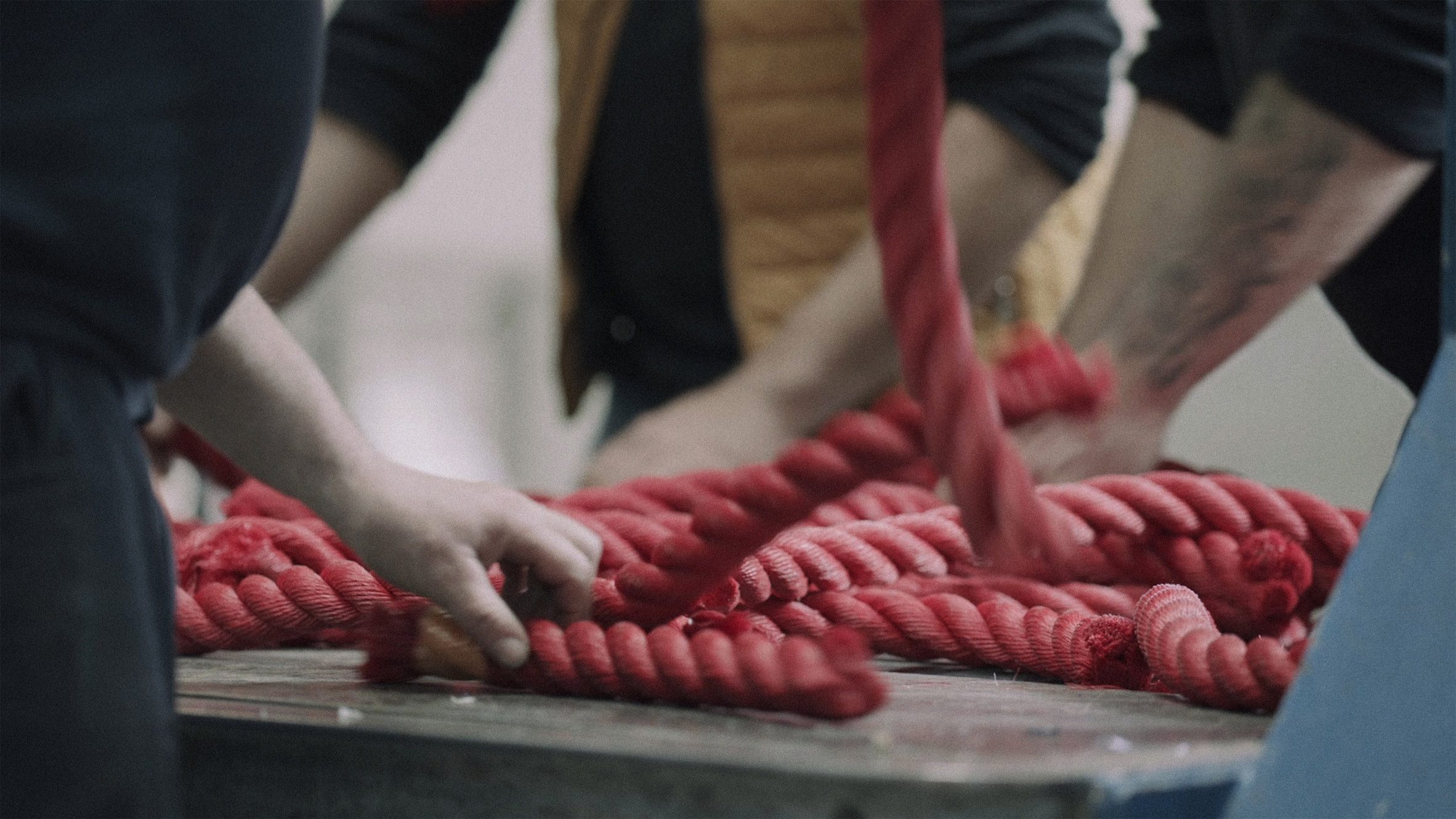 Photo of three sets of arms handling red ropes on a metal table