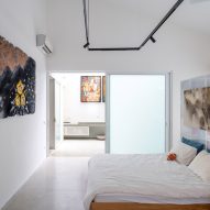 Bedroom with white walls, concrete flooring and sliding glass doors leading outside