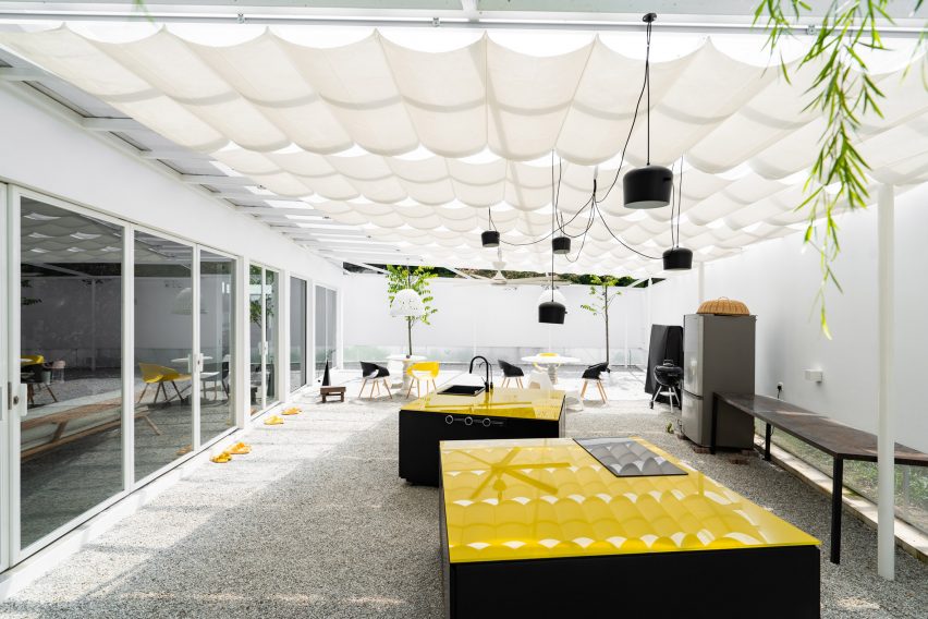 Covered outdoor courtyard with black and yellow kitchen appliances by Core Design Workshop