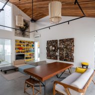 Double-height living space with white walls, concrete flooring and timber ceiling