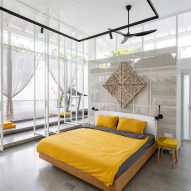 Double-height bedroom with large windows, concrete floor and yellow bedding
