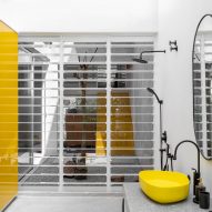 Bathroom with white screen wall and black and yellow sink and taps