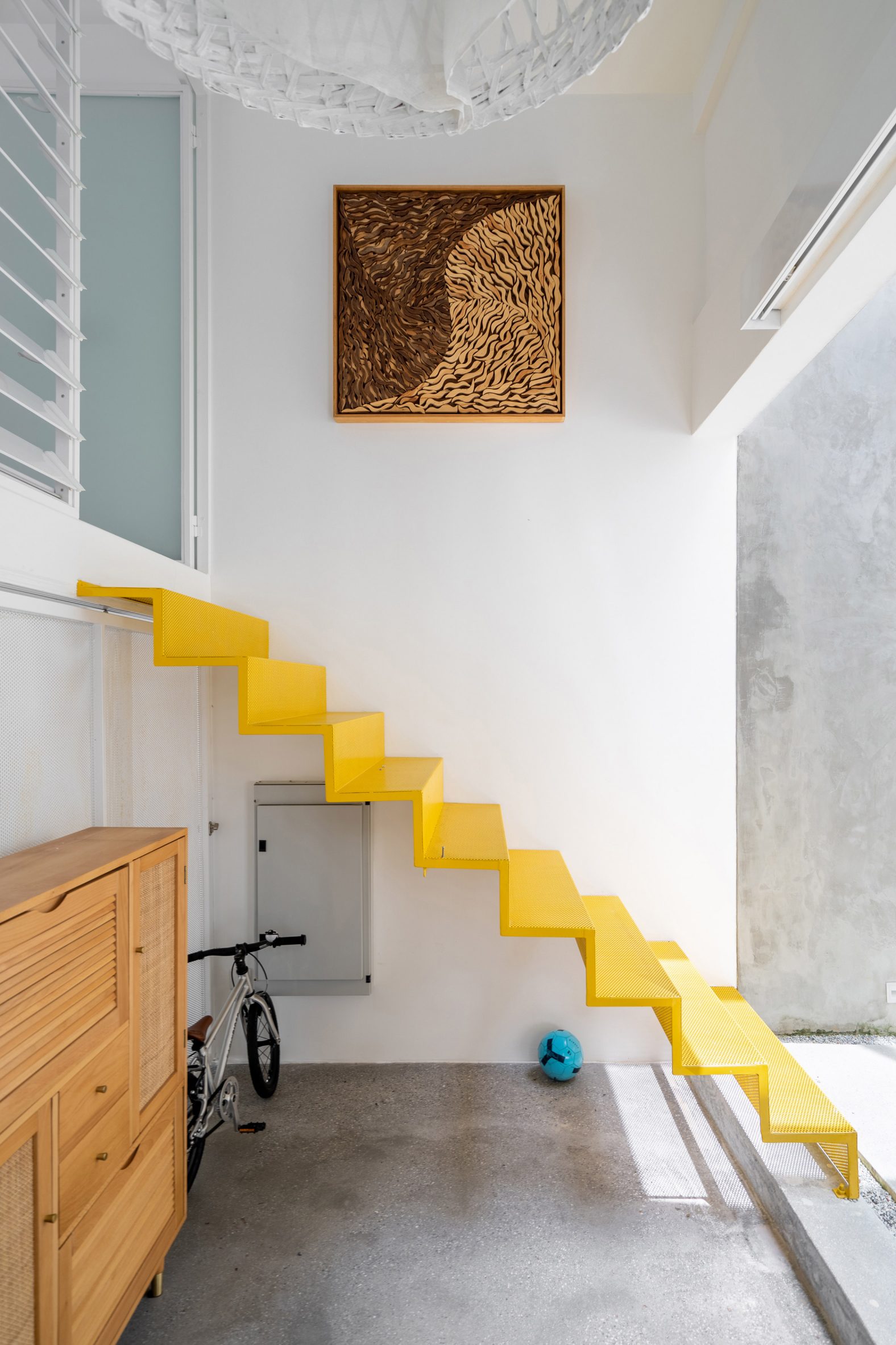 Yellow stairs in a white double-height space by Core Design Workshop