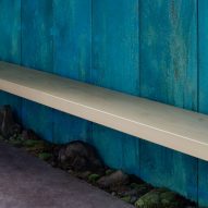 Wooden bench against a blue copper wall