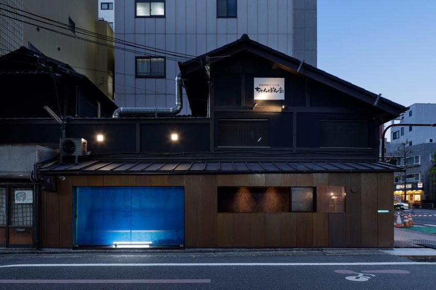 Edificio de madera negra con quiosco de cobre oxidado azul de G Architects Studio