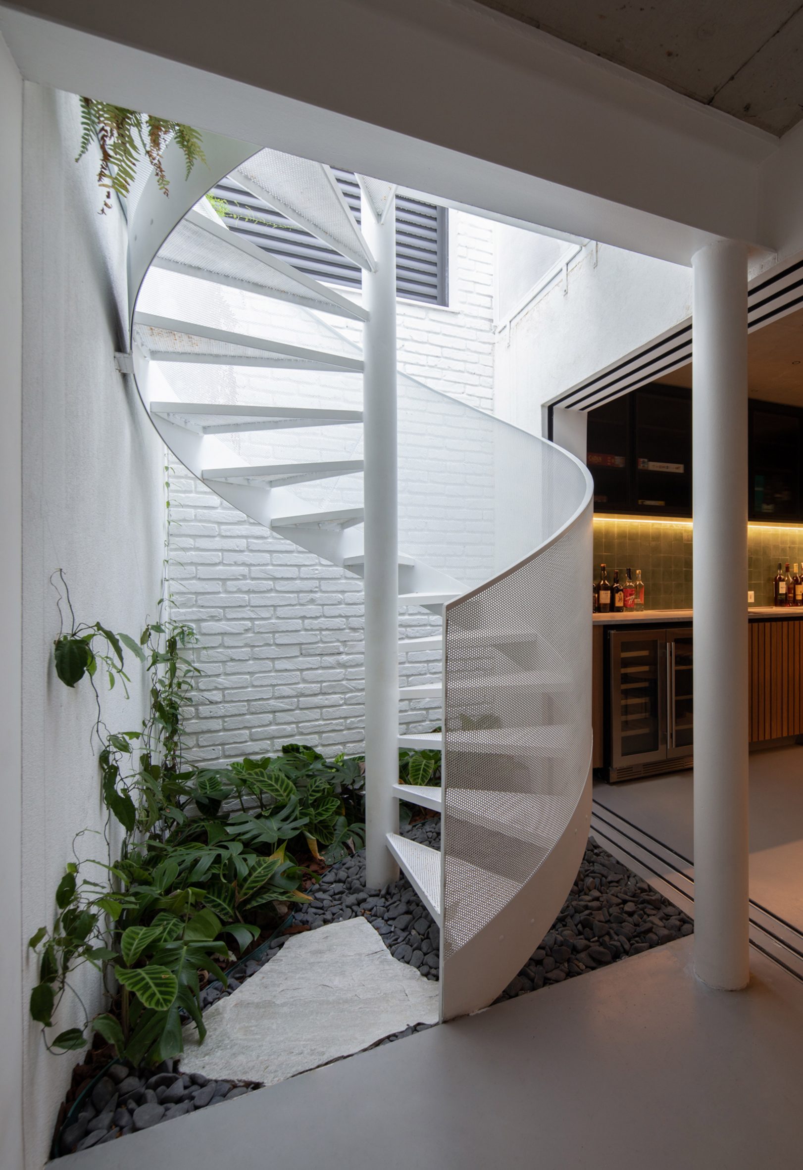 White spiral staircase leading to a basement with a bar
