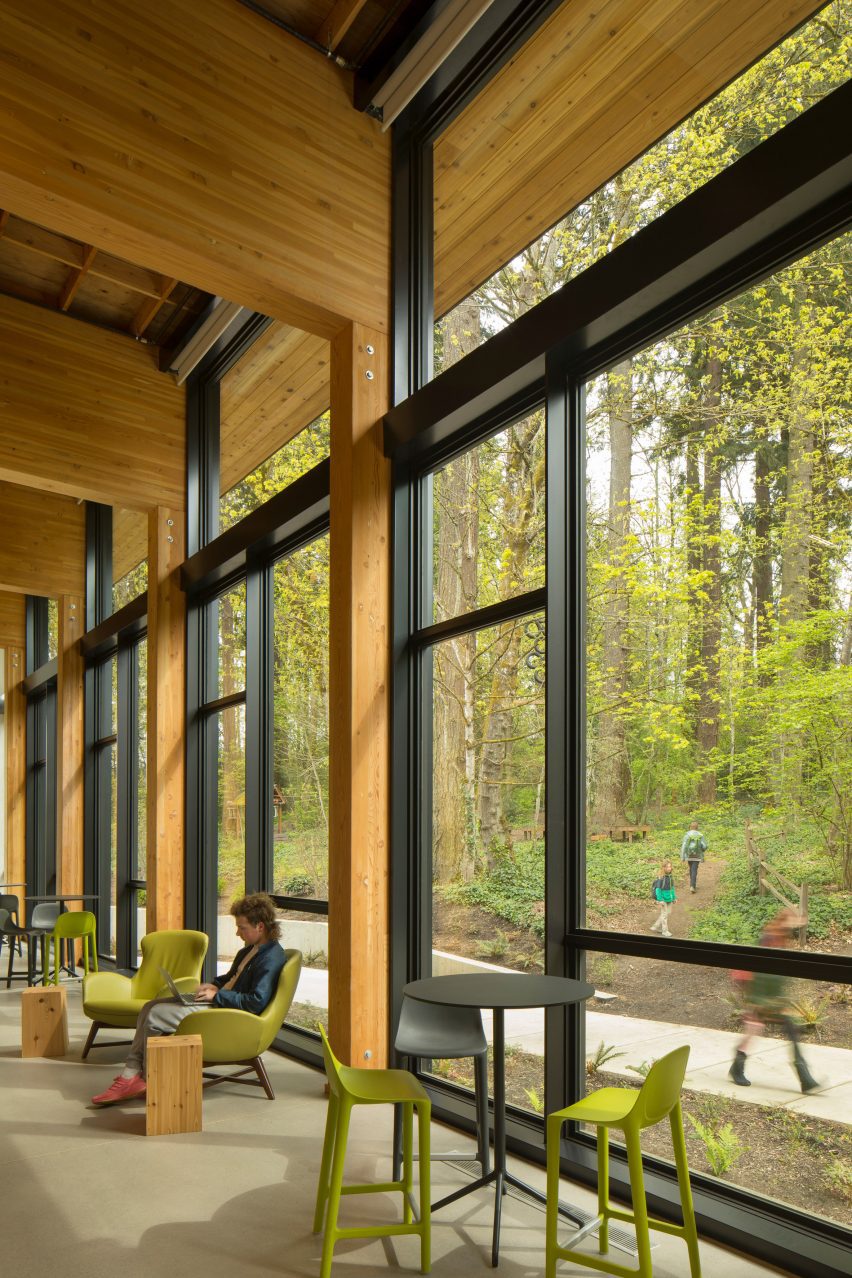 Timber structure with large windows overlooking a forest