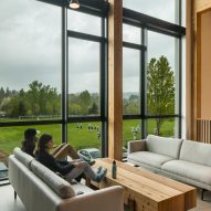 A timber study space with grey sofas beside a large window